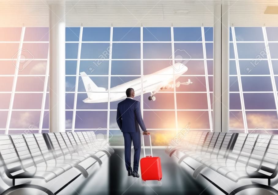 African American businessman in airport waiting area looking at large jet coming off the ground through panoramic window. Concept of business trips. Toned image