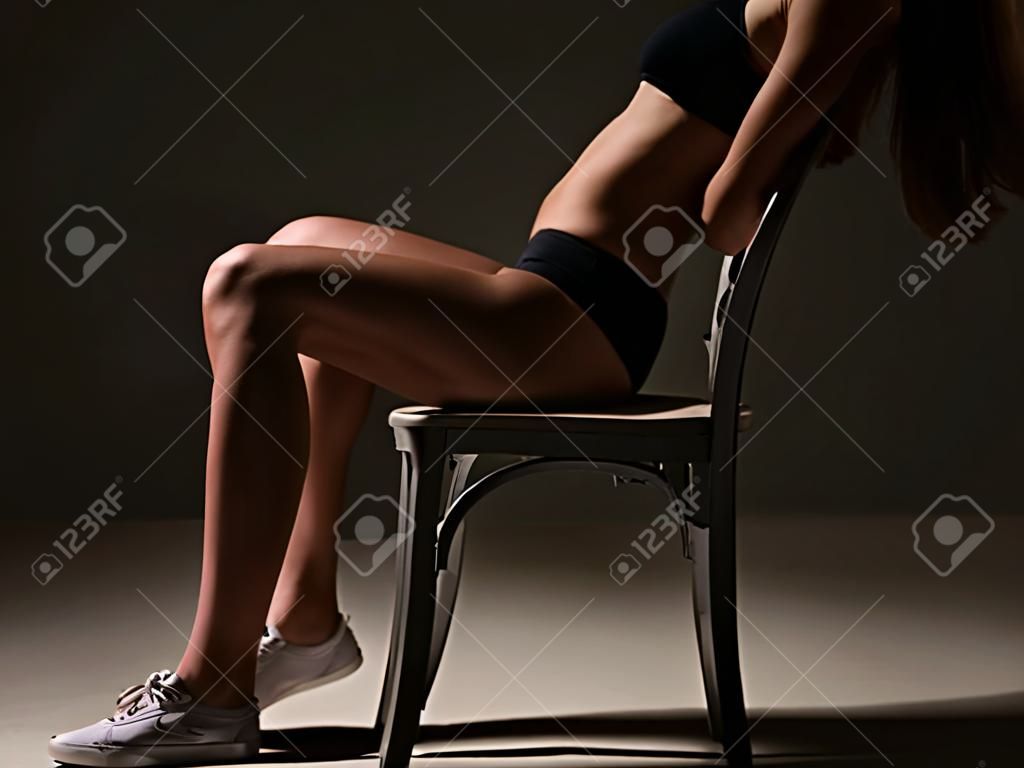 sagoma di una bella ragazza sportiva seduta sul bordo di una sedia gambe dritte. Uno stile di vita sano.