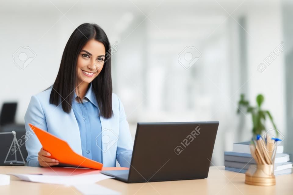 Portrait of smiling businesswoman looking at camera while working at office - image v