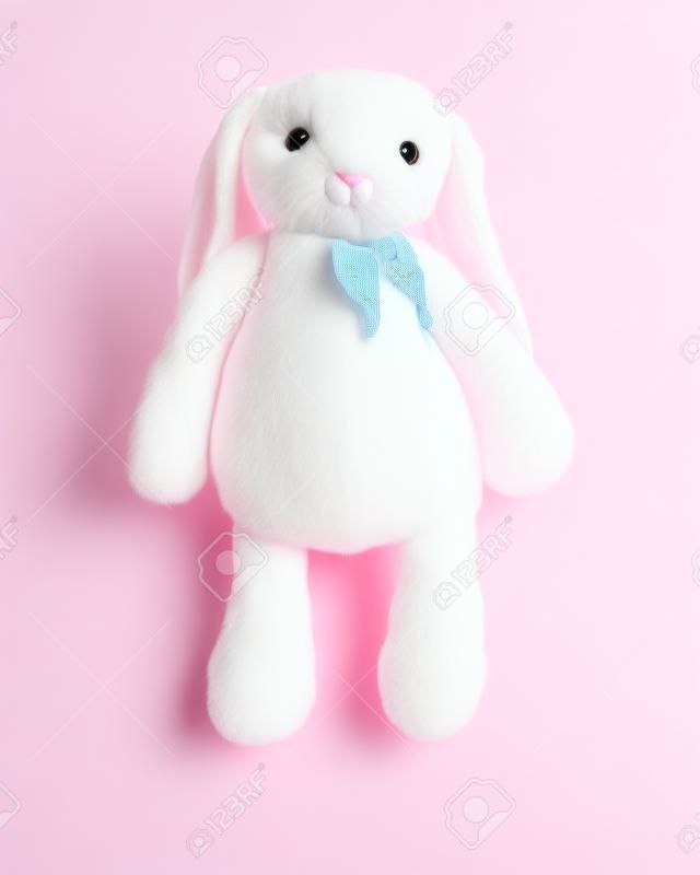 白い背景に孤立した大きな耳を持つピンクのウサギ人形。子供のためのかわいいぬいぐるみとふわふわの毛皮。