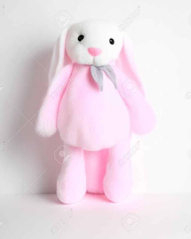 白い背景に孤立した大きな耳を持つピンクのウサギ人形。子供のためのかわいいぬいぐるみとふわふわの毛皮。