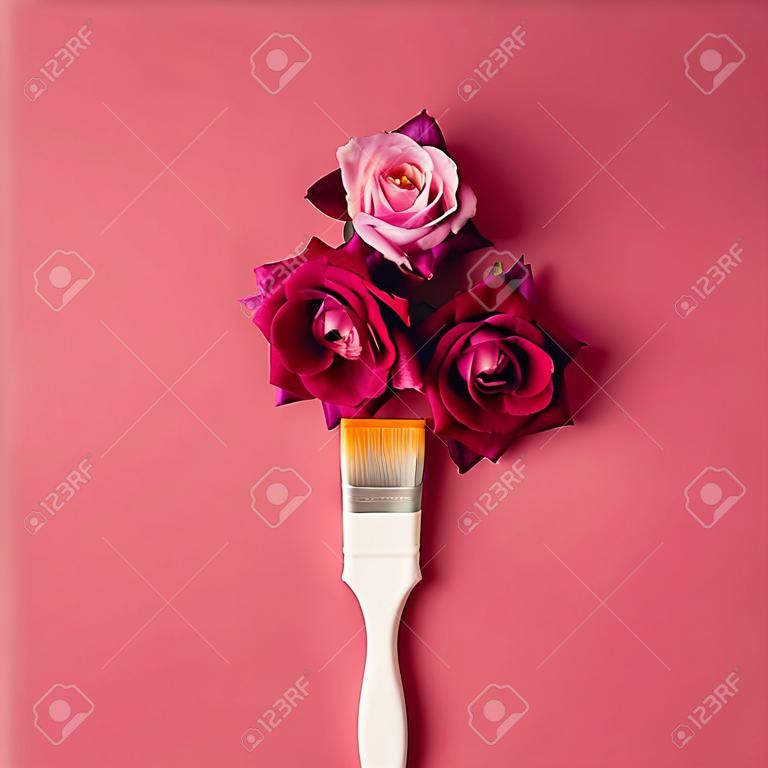 Fiori viola e pennello su sfondo rosa. Pianta piatta.