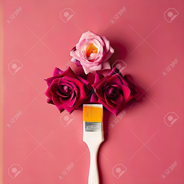 Paarse bloemen en verfborstel op roze achtergrond. Plat leggen.