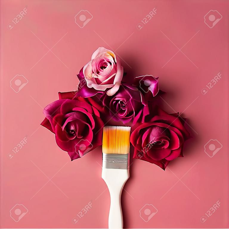 Paarse bloemen en verfborstel op roze achtergrond. Plat leggen.