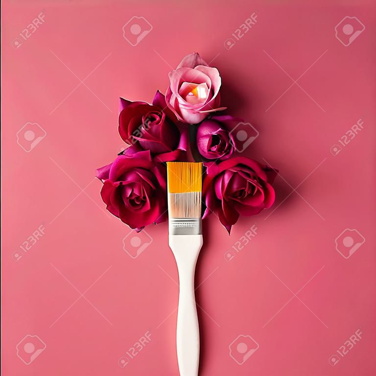Purple flowers and paint brush on pink background. Flat lay.
