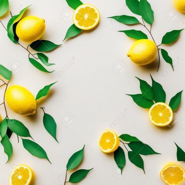 黄色の背景にレモンと黒の葉で作られた創造的な夏のパターン。フルーツミニマルコンセプト。フラットレイ。