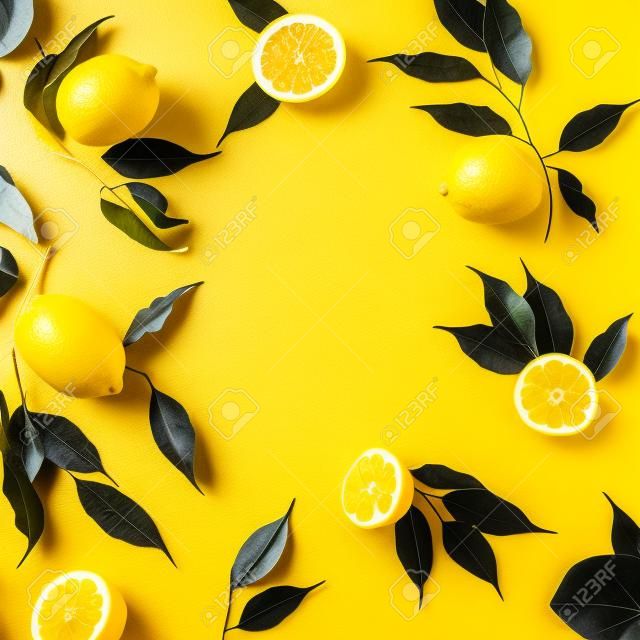 黄色の背景にレモンと黒の葉で作られた創造的な夏のパターン。フルーツミニマルコンセプト。フラットレイ。