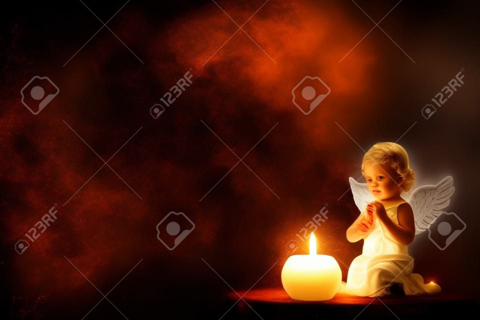 Angel and burning candle on black background