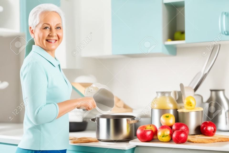Érett nő főz almaszósz jam a konyhában