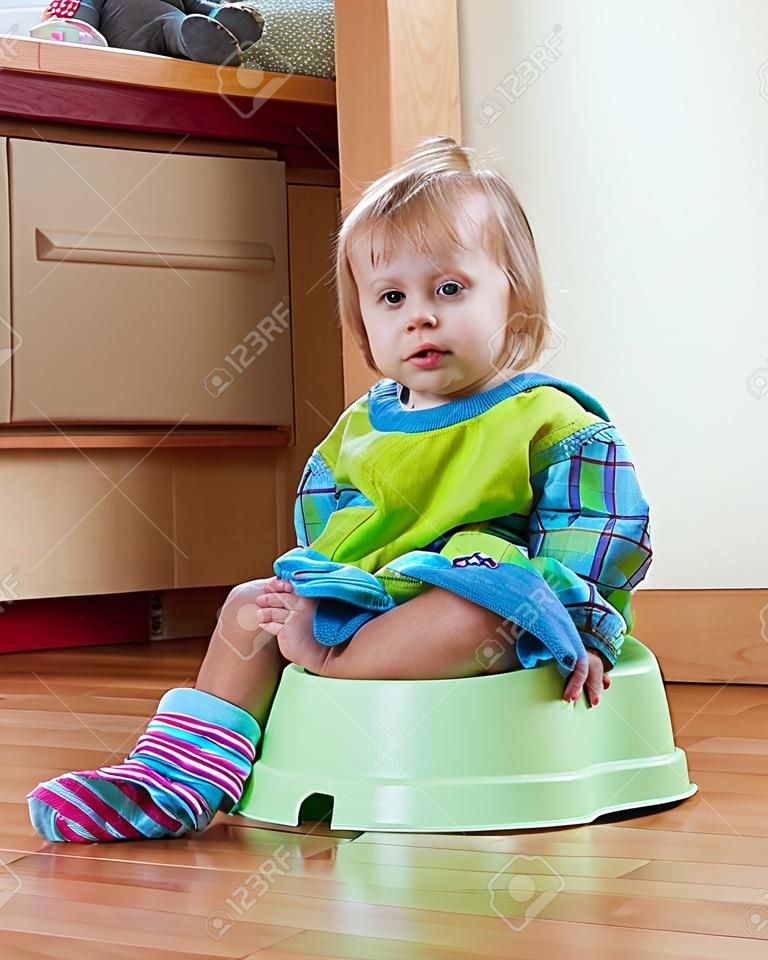 Baby girl sitting on potty in home 