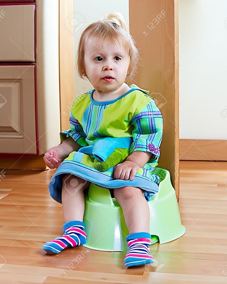 Baby girl sitting on potty in home 