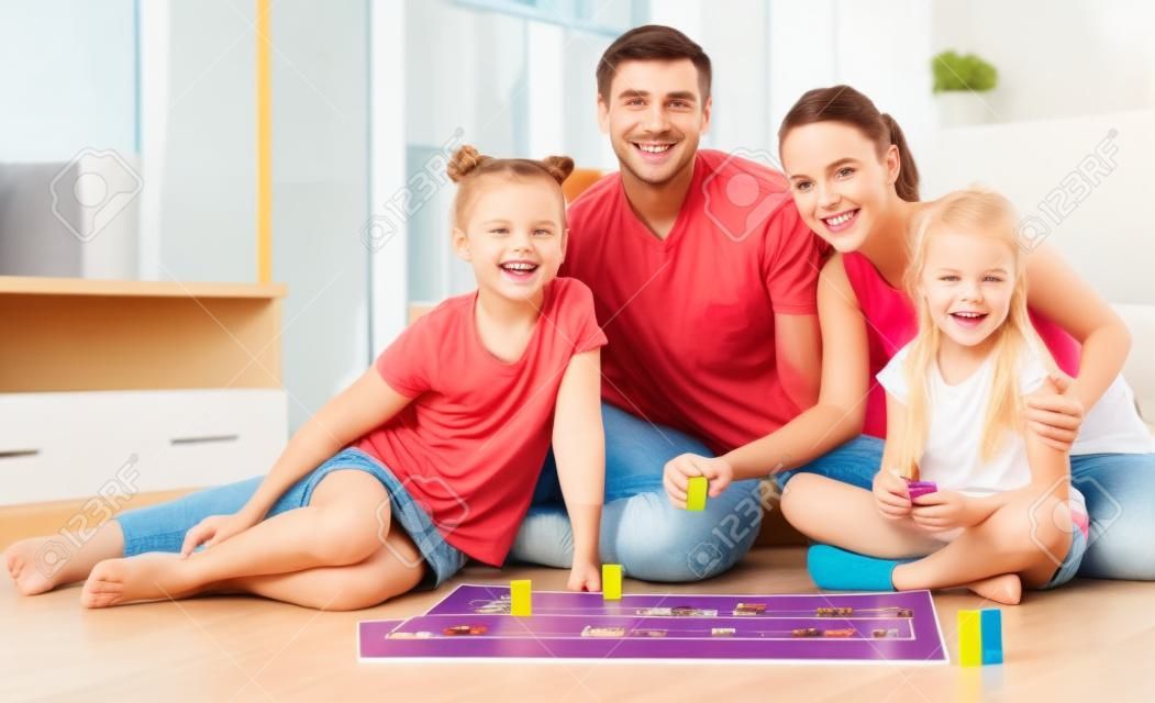 国内のインテリアでボードゲームで遊ぶ 4 つの若い家族の笑顔