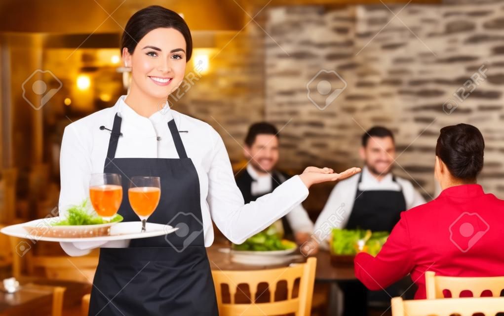 Camarera alegre bienvenida a los huéspedes al restaurante de campo