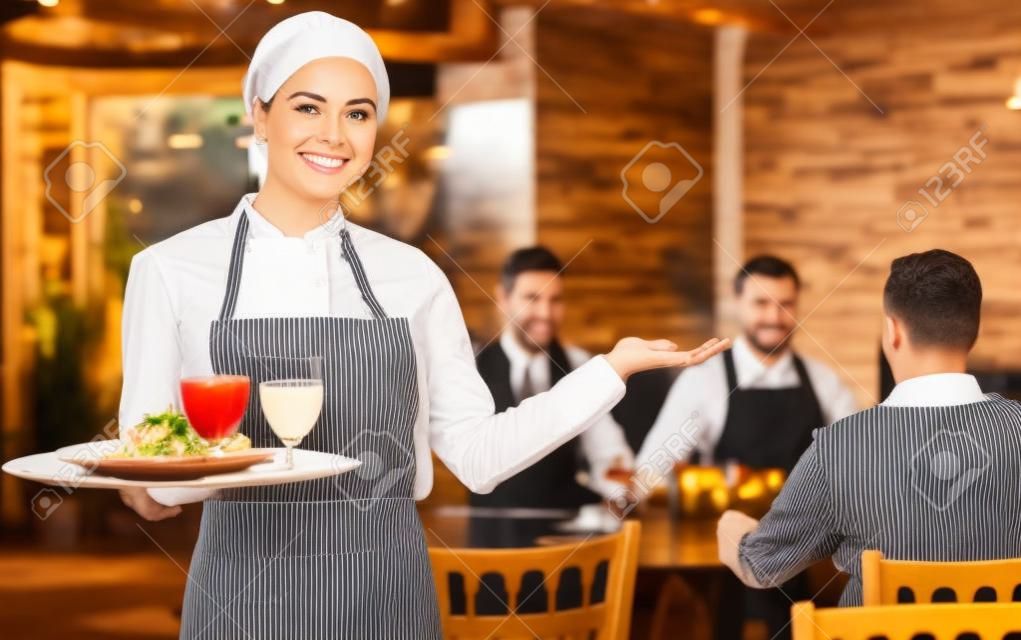 Camarera alegre bienvenida a los huéspedes al restaurante de campo