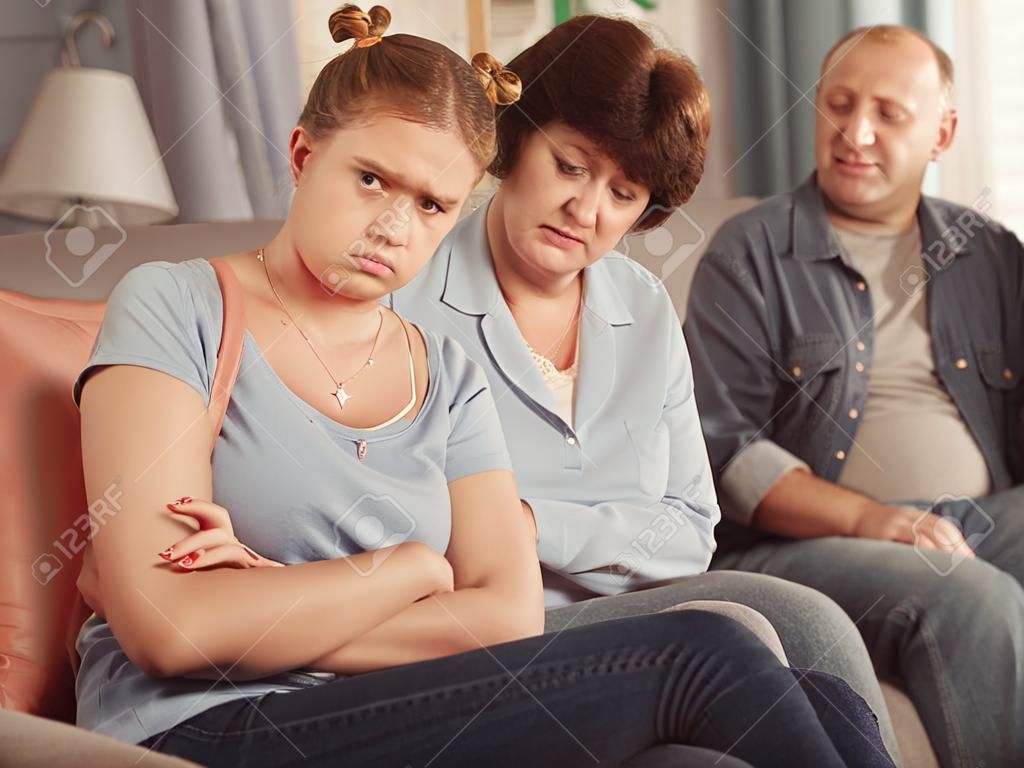 Mom and dad are supporting a sad daughter on sofa at home.