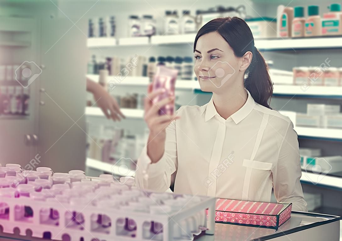 Cliente femminile allegra che cerca prodotti per la cura del corpo in farmacia