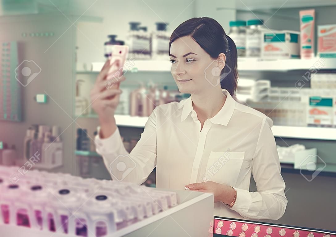 Cheerful female customer looking for products of body care in pharmacy