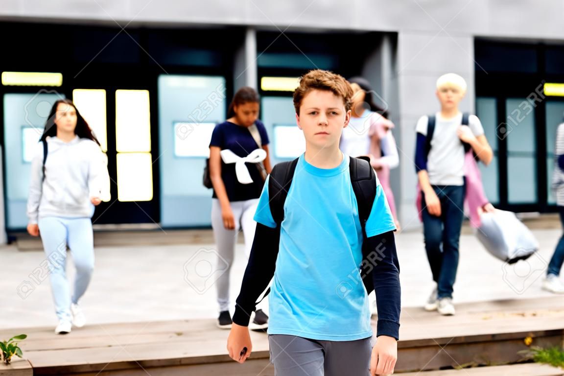 Positive teenager walking in the street carrying bag on one shoulder