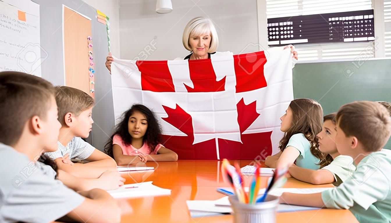 Female teacher showing canadian flag to kids in geography class