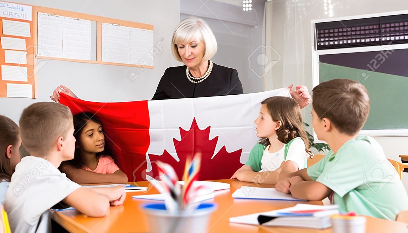Female teacher showing canadian flag to kids in geography class