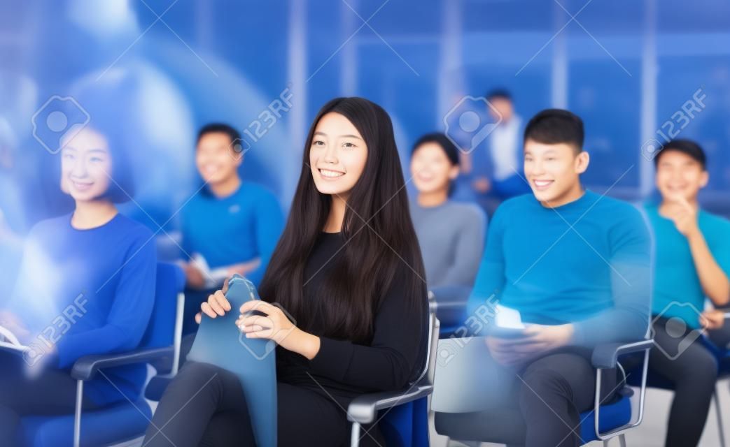 Young asian girl sitting in lecture hall with group