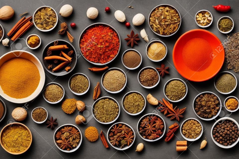 Illustrative flatlay of many different spices in bowls, bright and colorful.