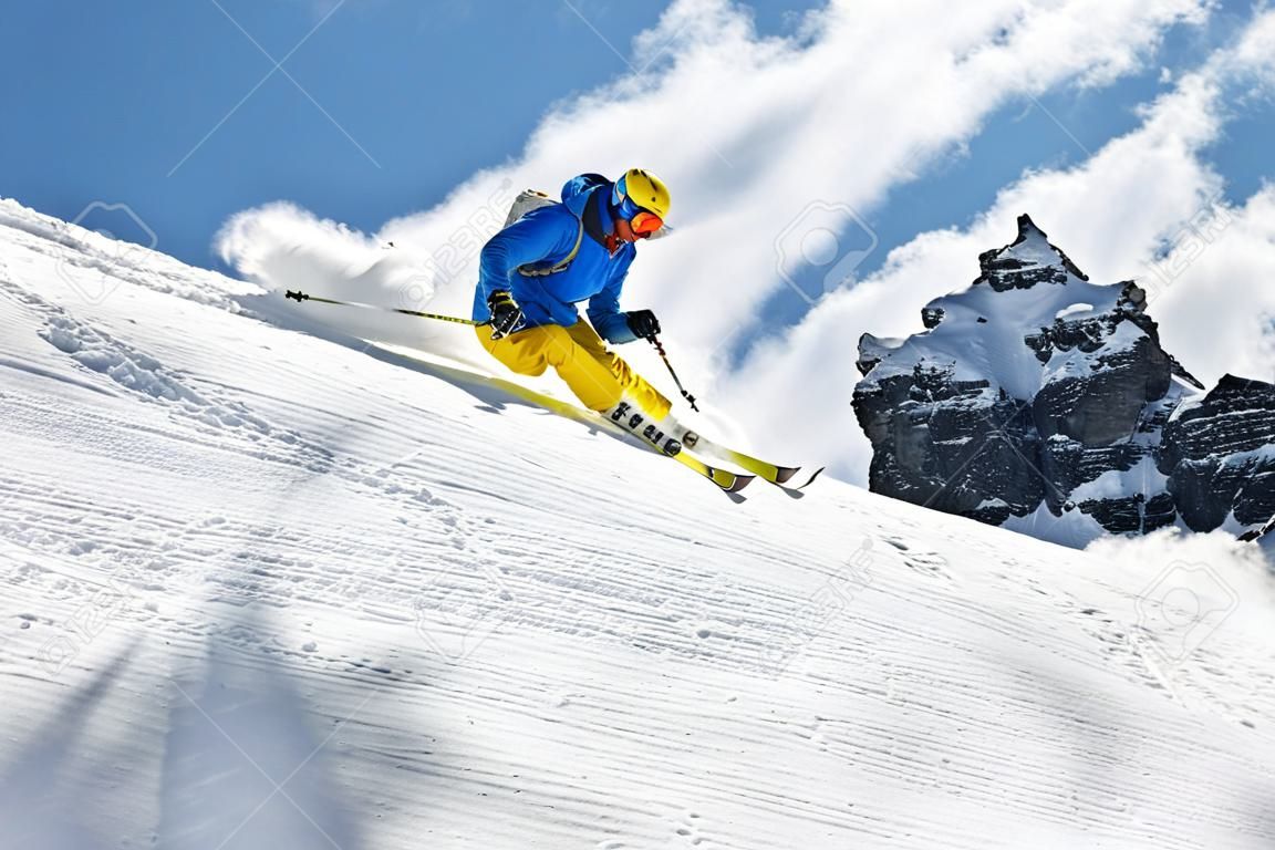 男滑雪者在下坡的自由式滑雪與太陽和山景