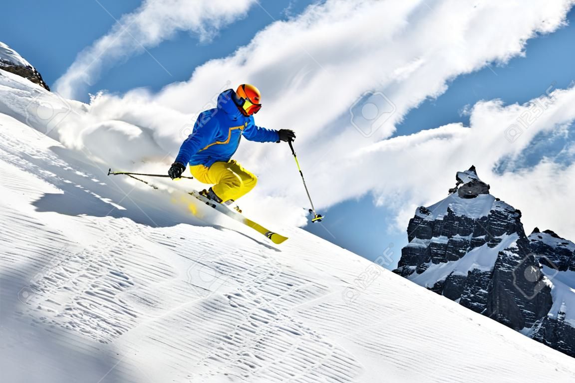 Męska narciarka na zjazdowym freeride z słońcem i widokiem górskim