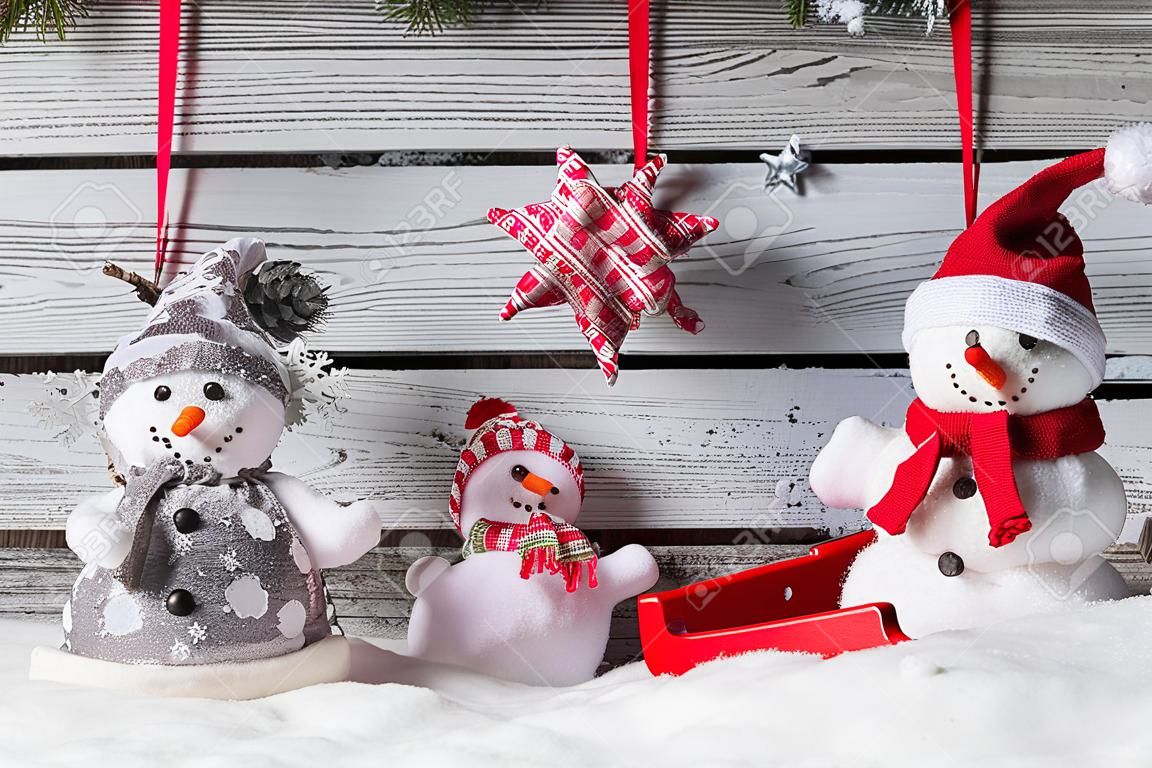 Christmas still life decoration of snowmen with sledge on wooden background.