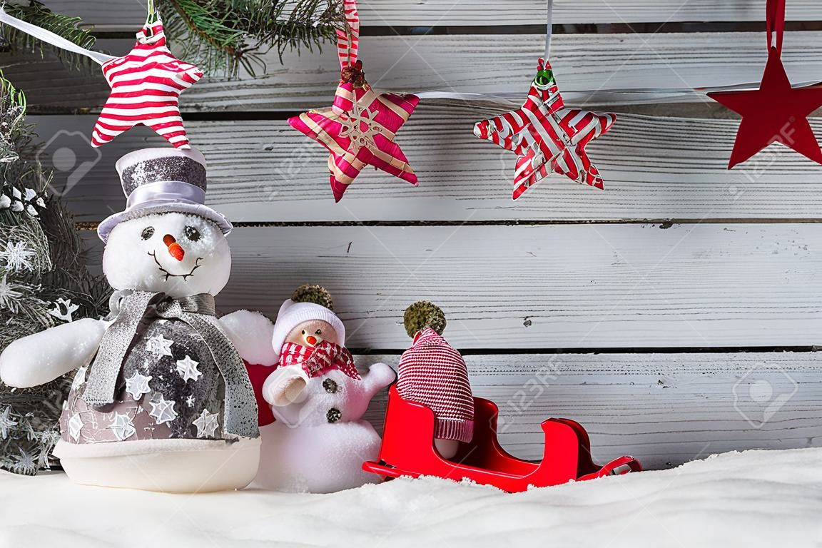 Christmas still life decoration of snowmen with sledge on wooden background.