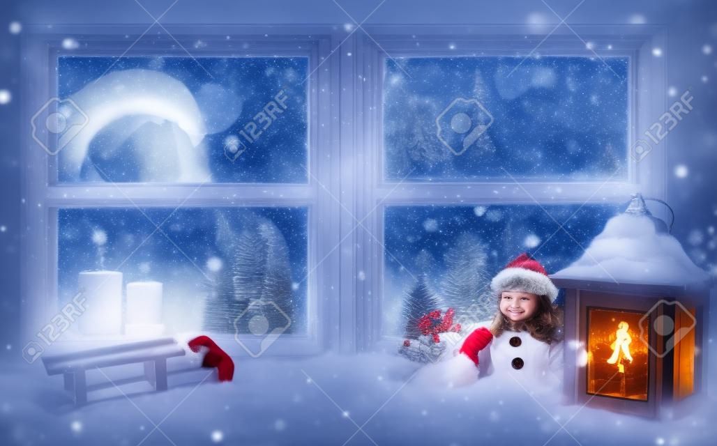 Atmospheric Christmas window with Santa girl looking out of glass. Concept of Christmas evening