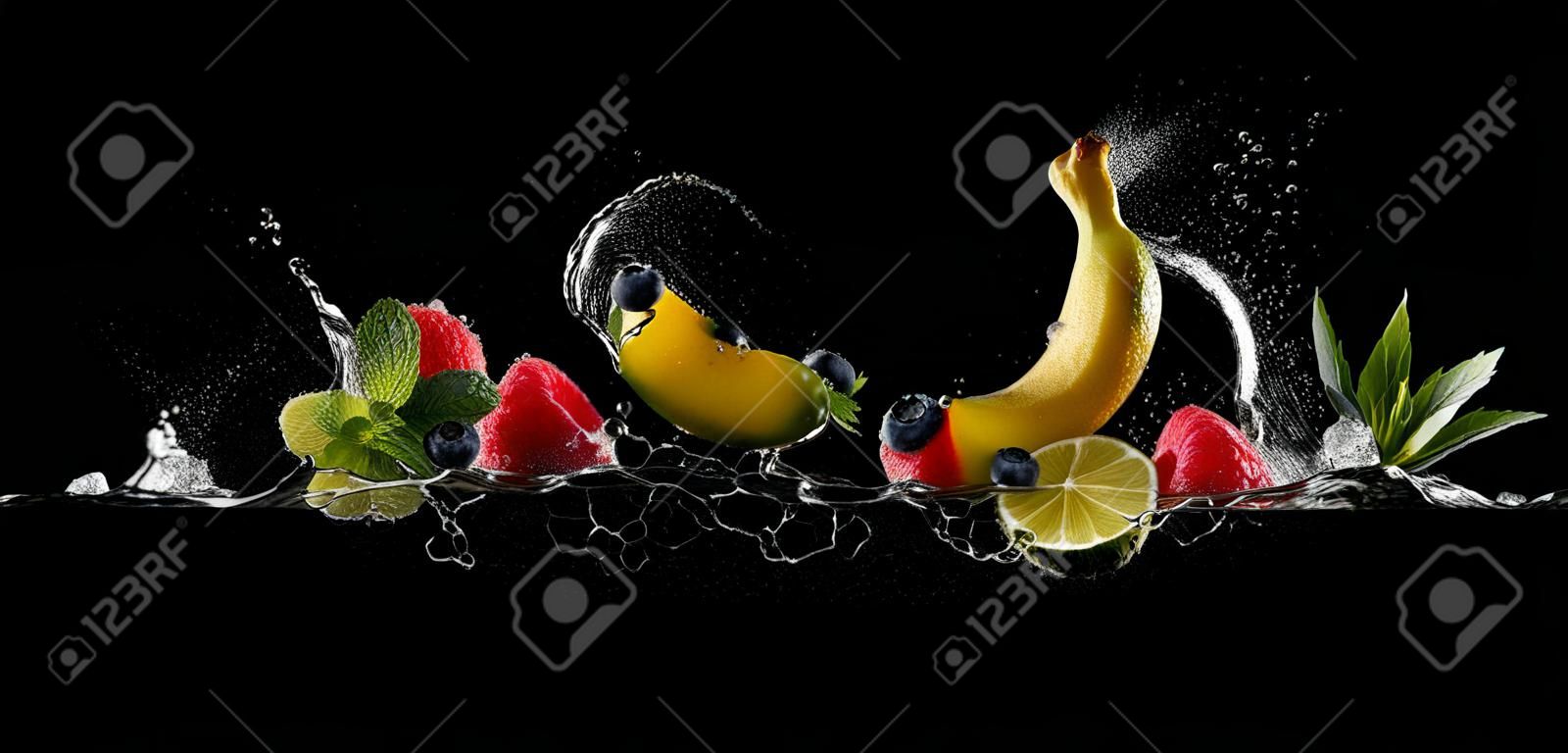 Pieces of fruit with mint leaves and ice cubes, falling in water splash, isolated on black background.