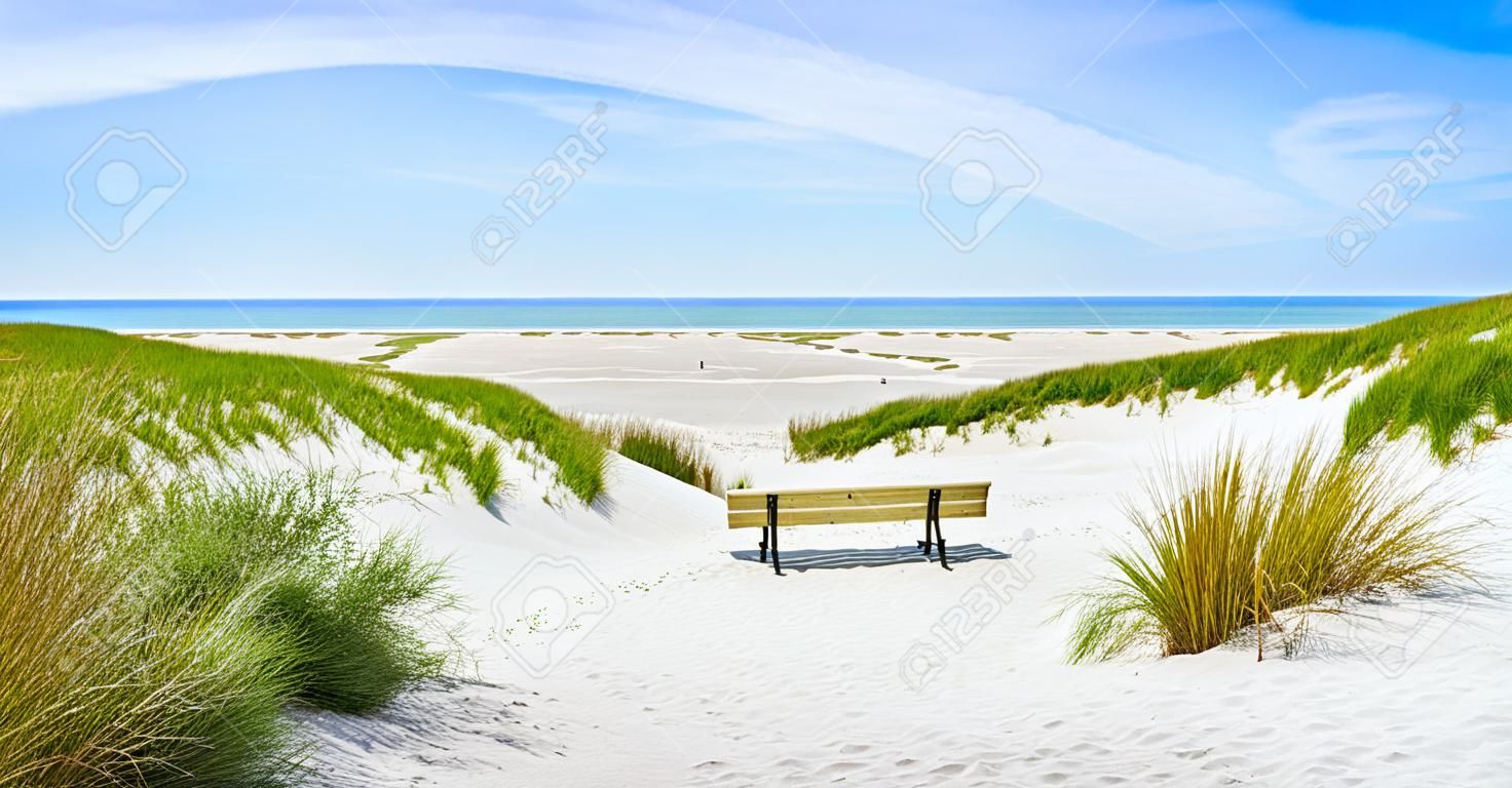Beautiful tranquil dune landscape with idyllic bench overlooking the German North Sea and a long beach on the island of Amrum, Schleswig-Holstein, Germany