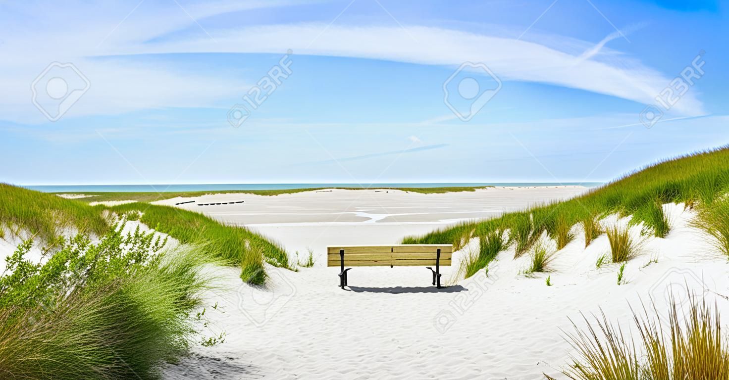Beautiful tranquil dune landscape with idyllic bench overlooking the German North Sea and a long beach on the island of Amrum, Schleswig-Holstein, Germany