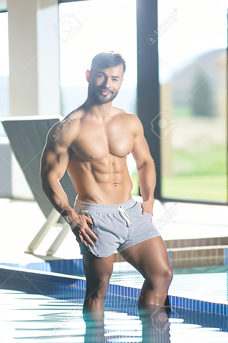 Atleta modelo joven saludable y apuesto Macho Man en la piscina cubierta del hotel