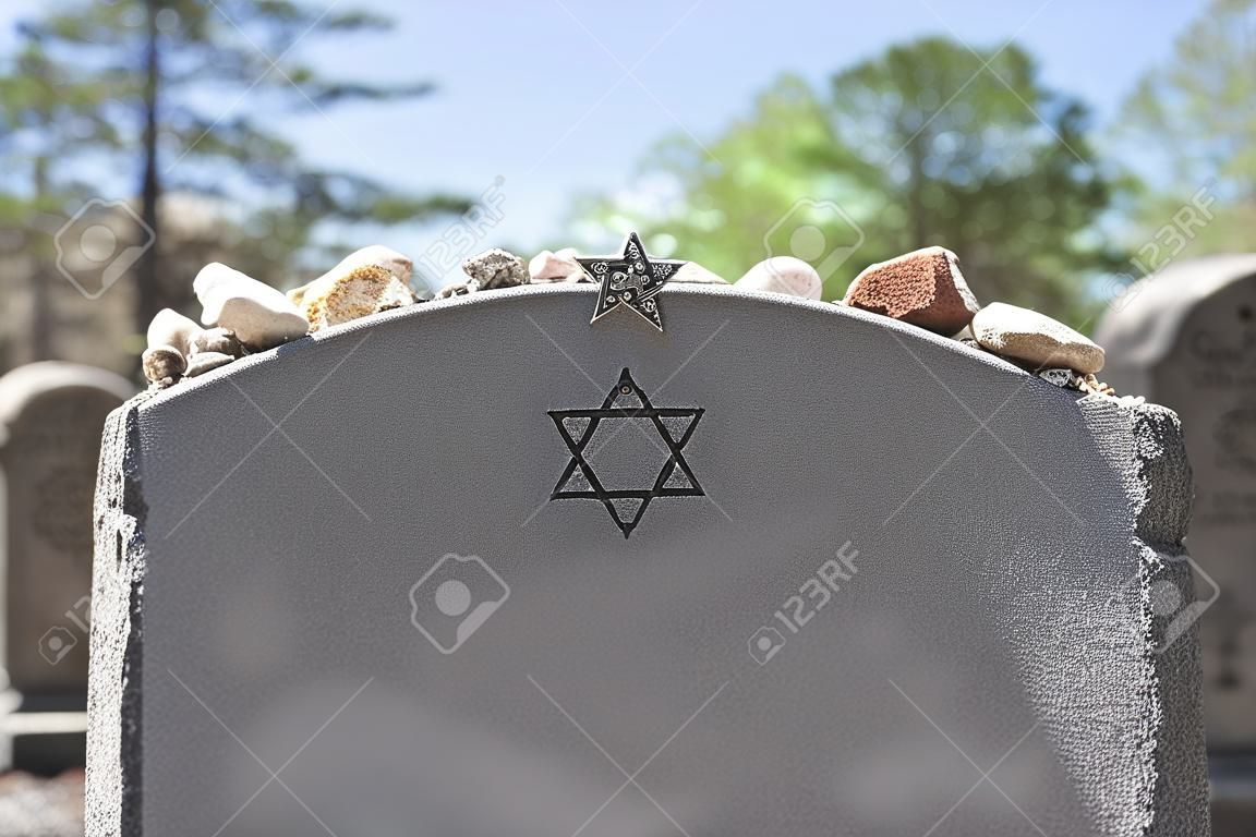 Lápida en un cementerio judío con la Estrella de David y piedras de memoria. Enfoque selectivo en primer plano. Copie el espacio.
