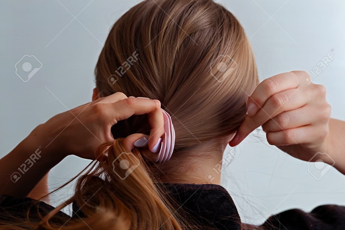 Mujer rubia natural haciendo una cola de caballo, sosteniendo su cabello, detener el movimiento, vista trasera,
