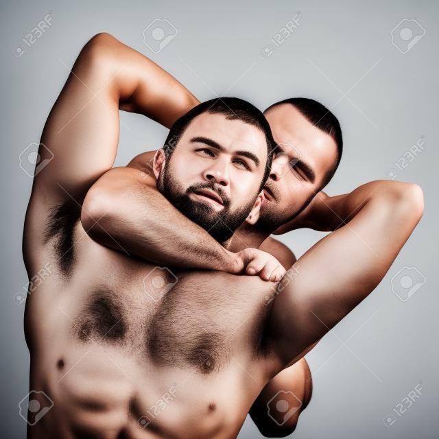 Dos hombres sin camisa luchando y luchando, aislados en fondo blanco.