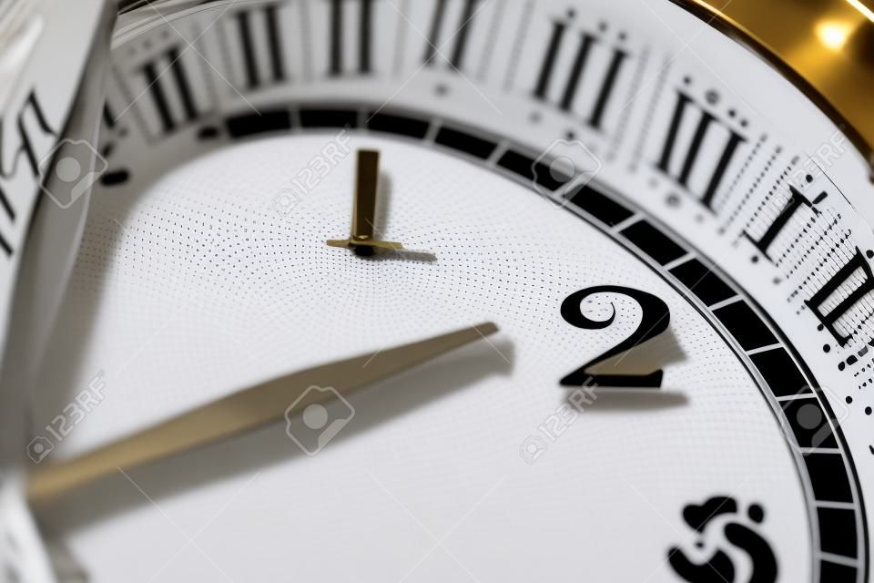 Clock hand pointing two o'clock on white clock face of Twin bell classic alarm clock
