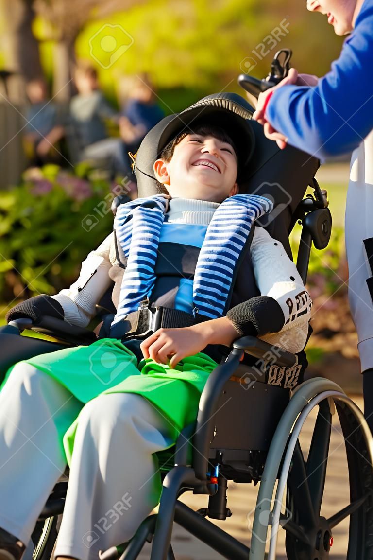 Smiling nine year old boy in wheelchair enjoying time at park outdoors