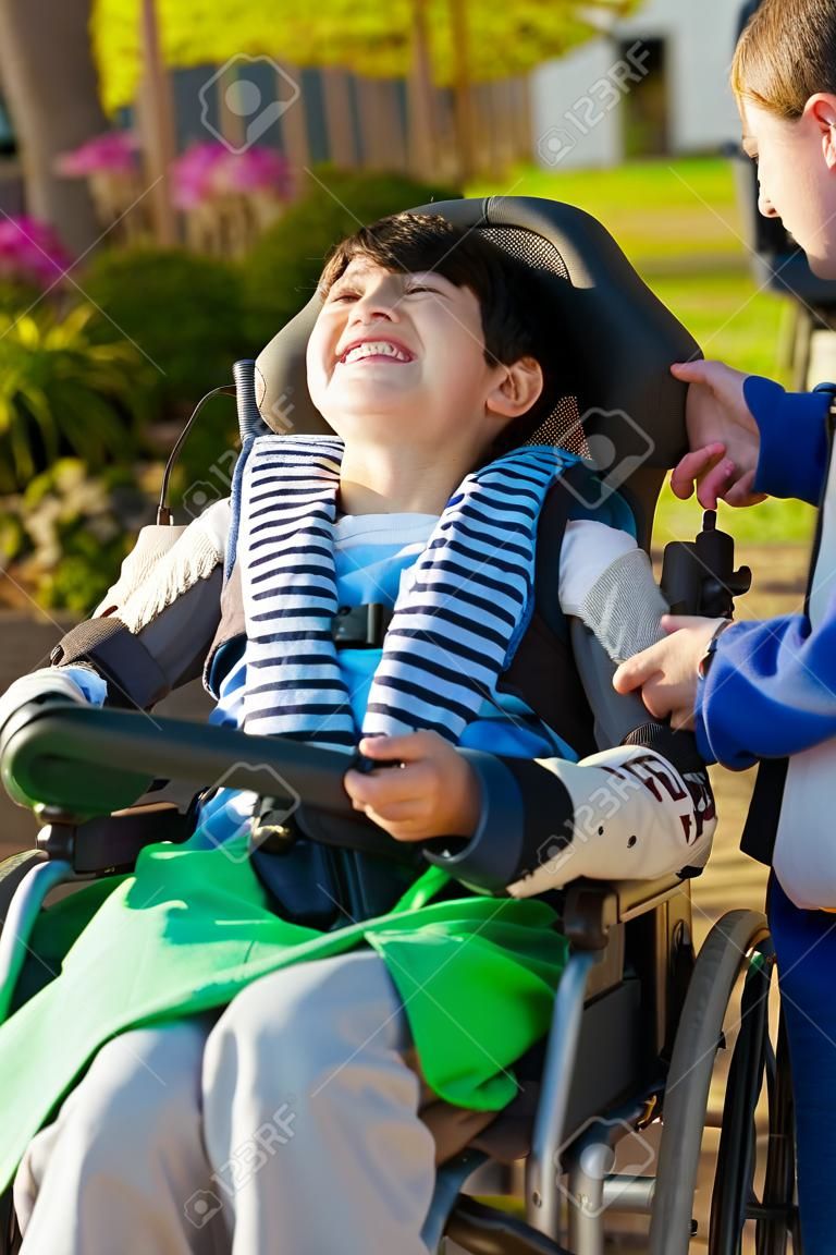 Smiling nine year old boy in wheelchair enjoying time at park outdoors