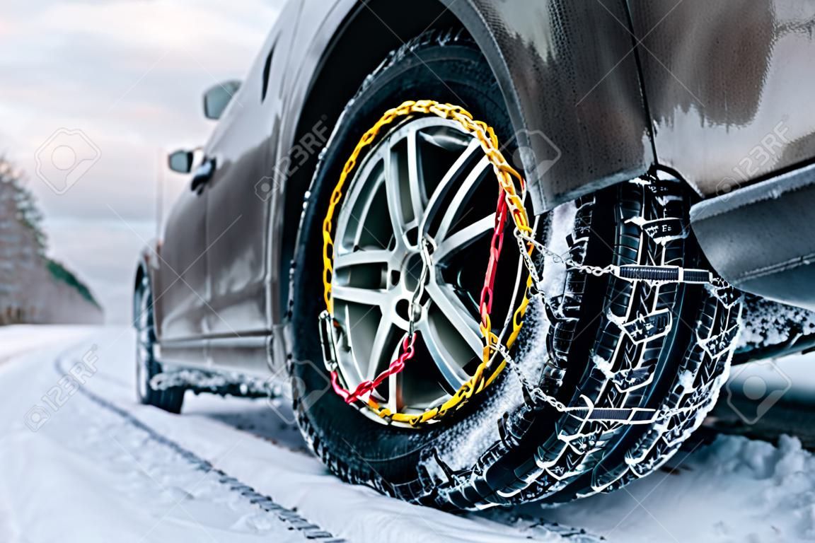 Catene da neve sul pneumatico. Particolare della ruota su strada invernale