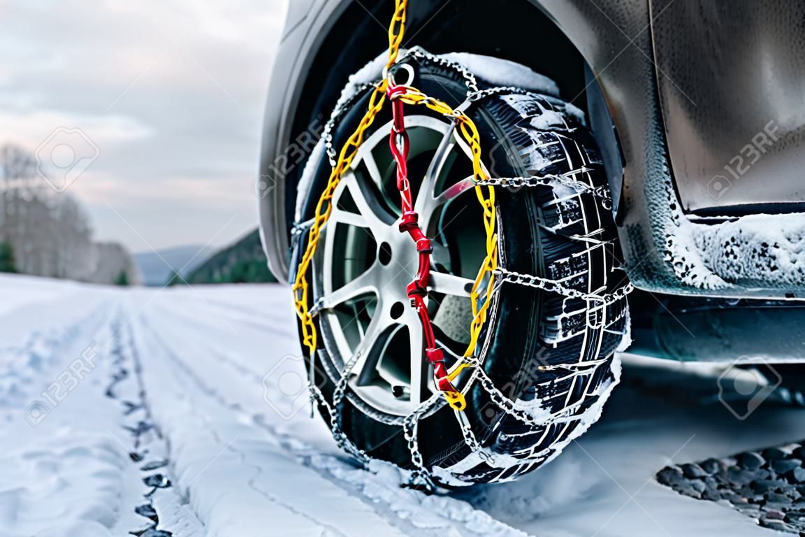 Catene da neve sul pneumatico. Particolare della ruota su strada invernale