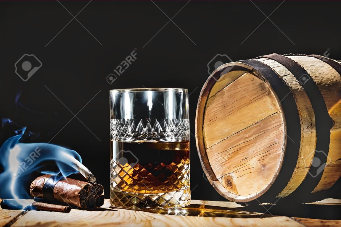 Glass of alcohol and smoking cigar on a black background noble
