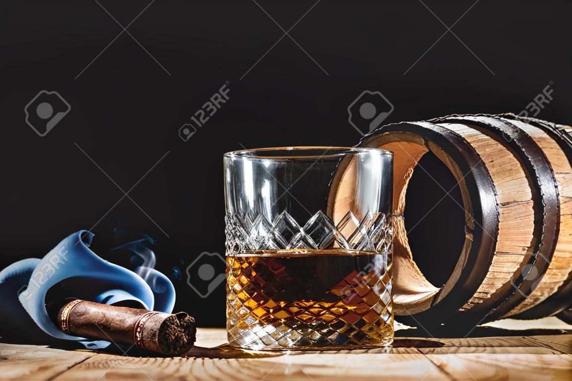 Glass of alcohol and smoking cigar on a black background noble
