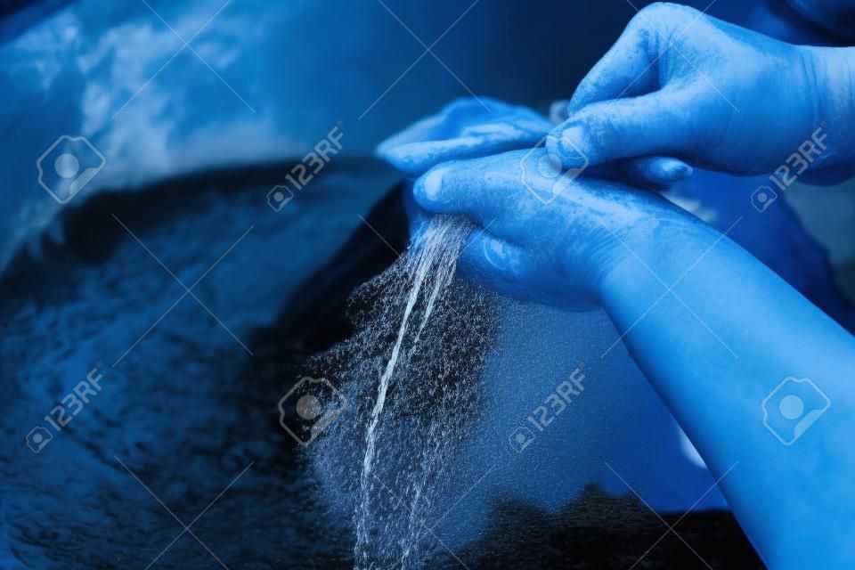 Mãos da mulher que lavam a roupa preta na bacia azul