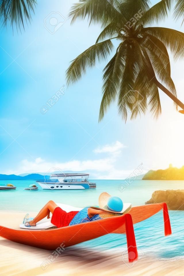 Concepto de vacaciones en la playa de verano, mujer asiática con sombrero relajándose y en la playa de sillas con lancha rápida en Koh Payam, Ranong, Tailandia