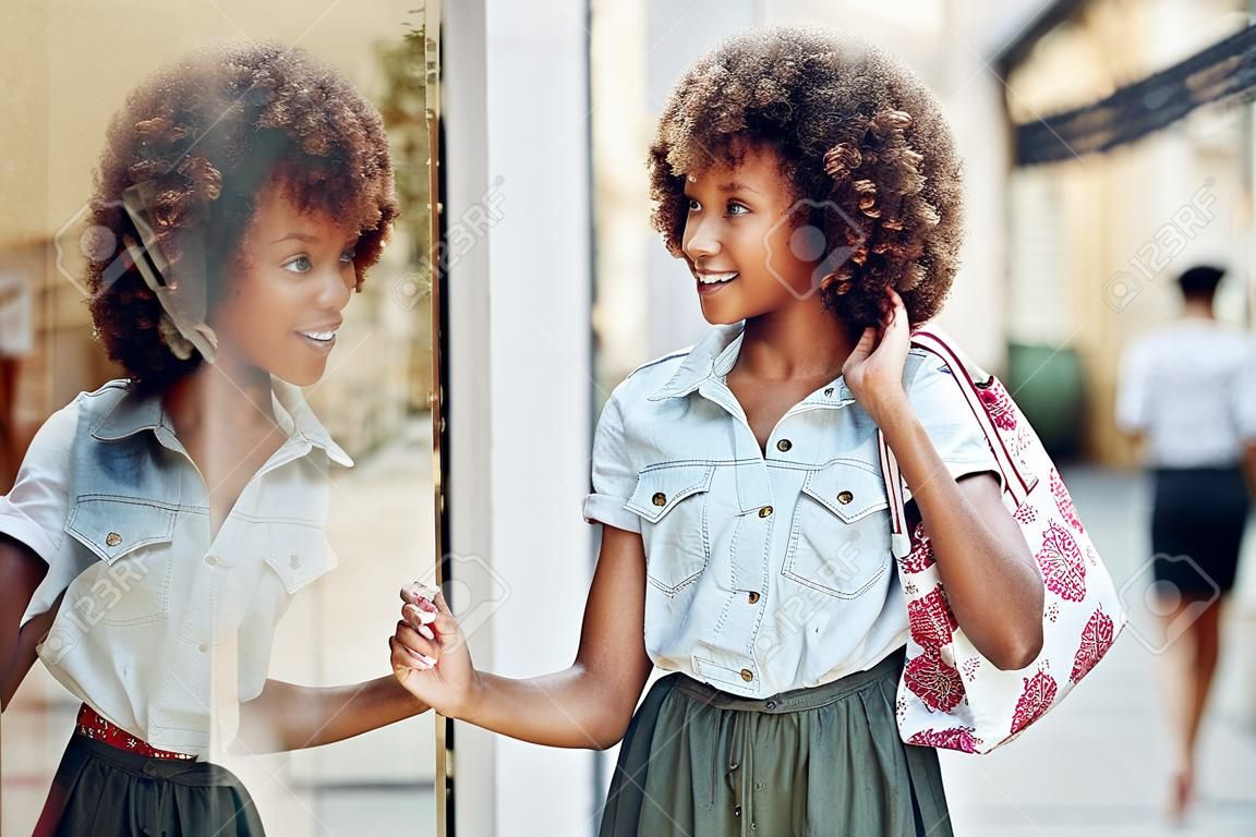 jeune femme noire devant une vitrine dans un panier de fille avec une fille afro de afro avec des gants de coiffure afro