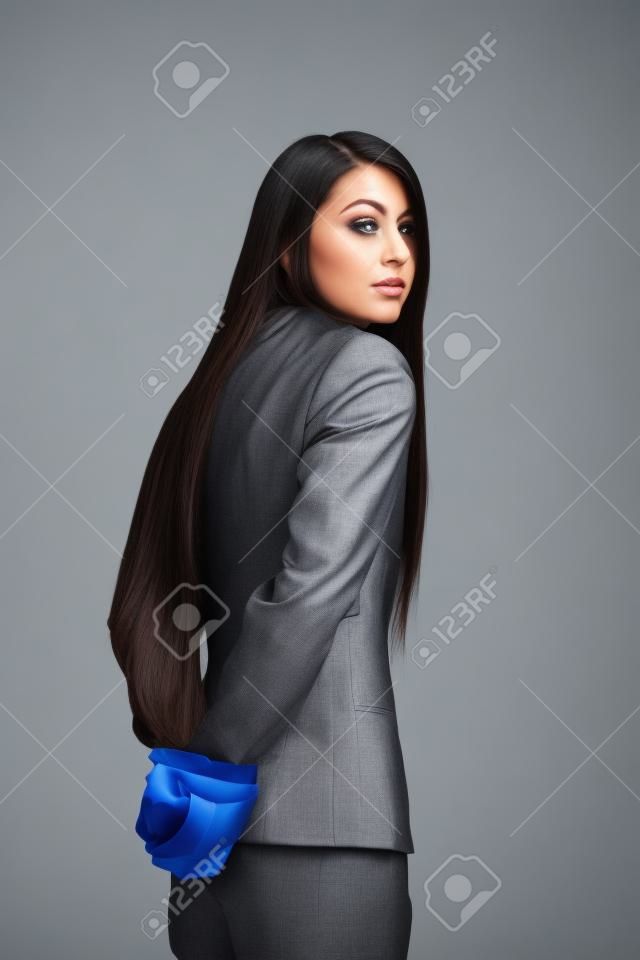 femme vêtue d'un costume d'affaires avec sa main attachée derrière le dos