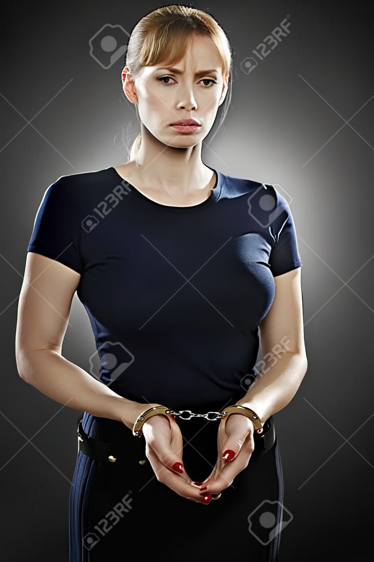 business woman with her wrists handcuffed together looking worried.
